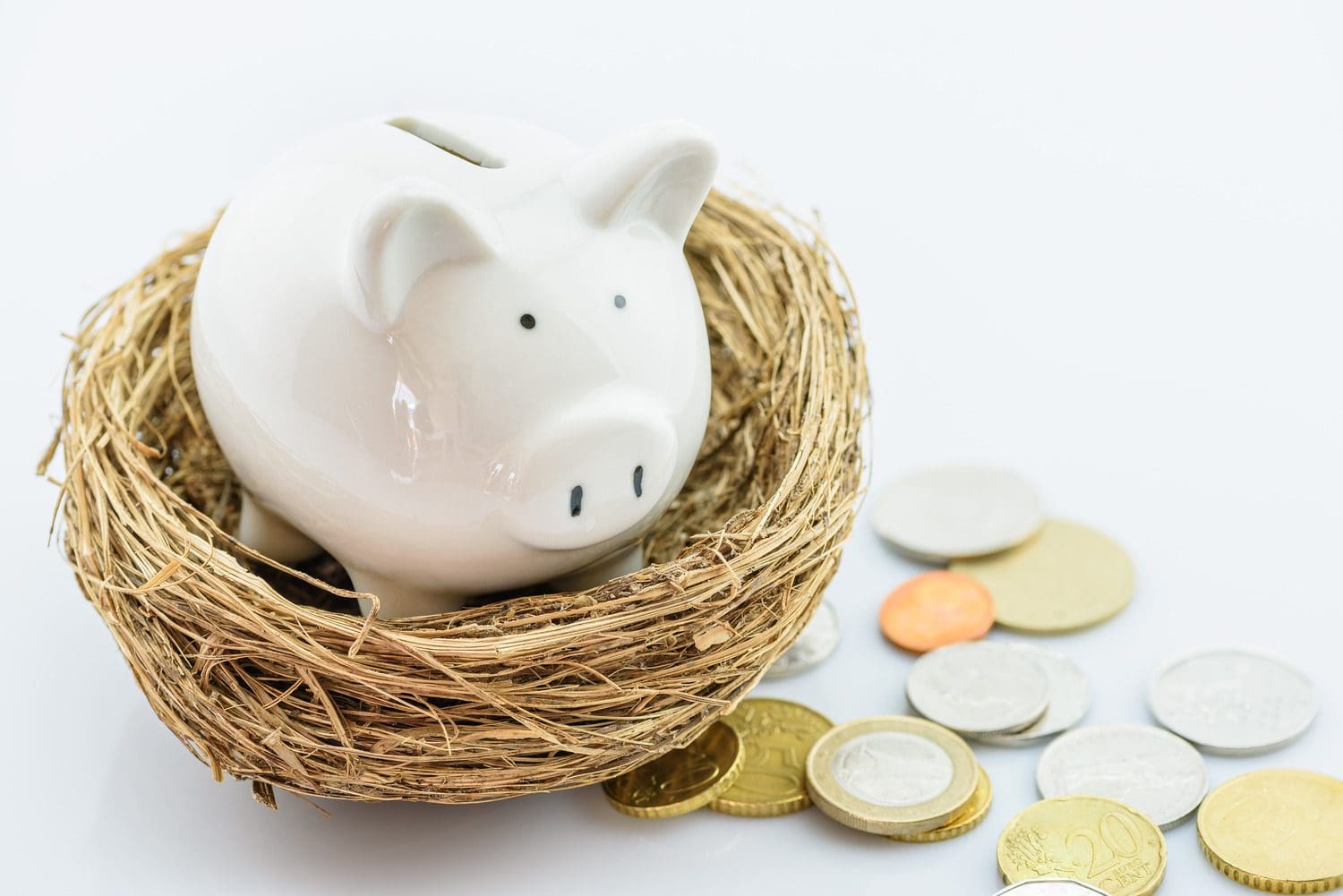 White piggy bank with scattered coins