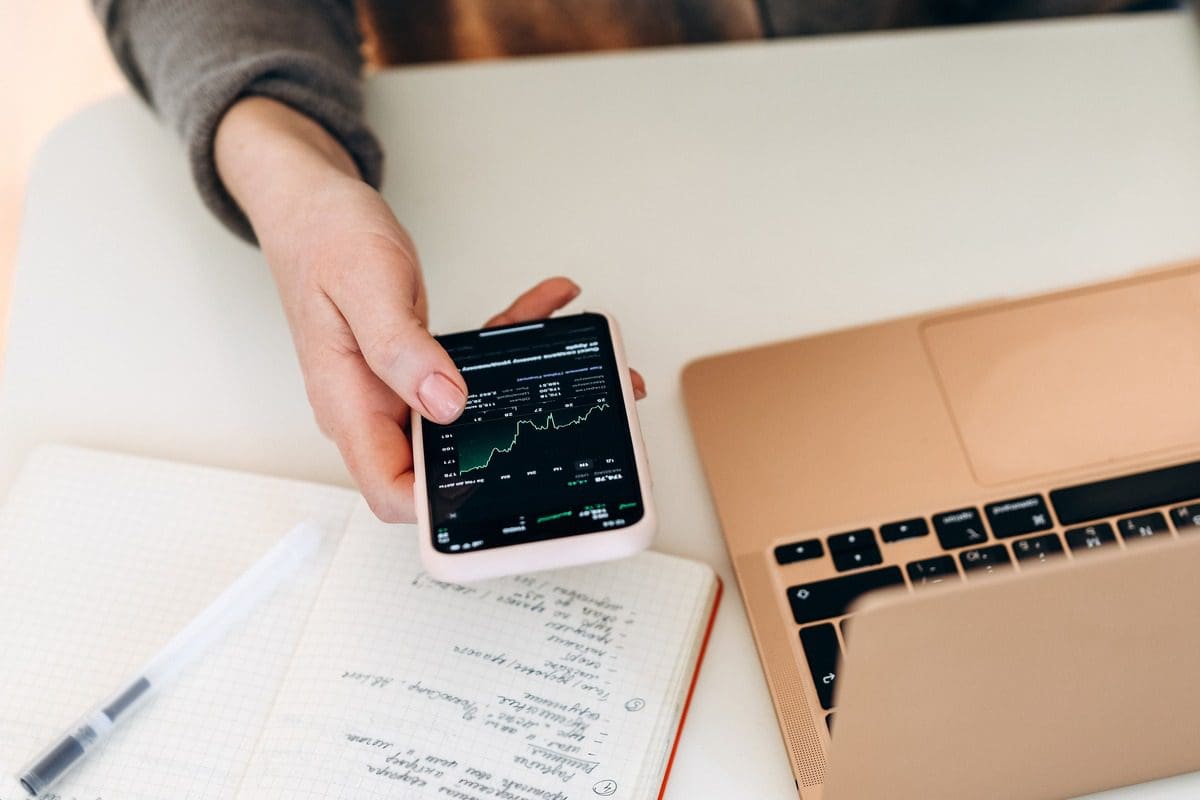 Person using a smartphone to view stock market charts and investment data.