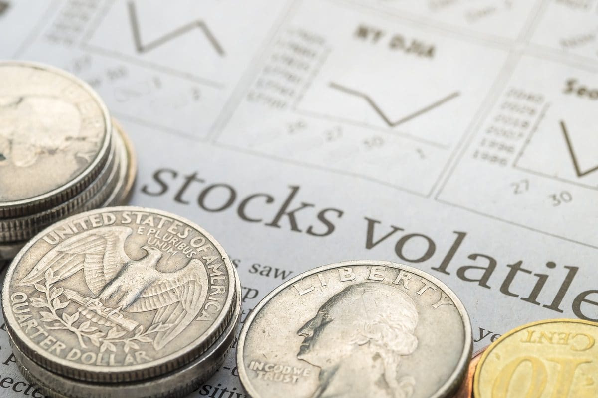 U.S. currency on a newspaper headline discussing stock market volatility and economic analysis.