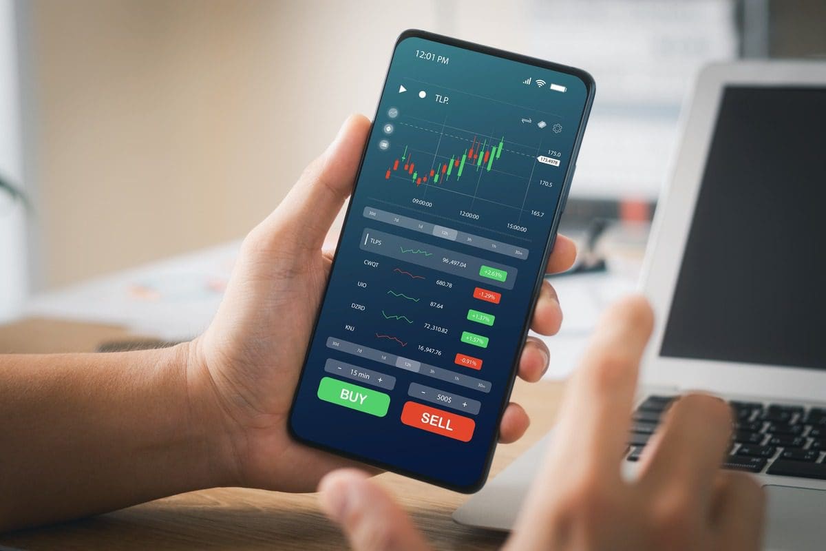 Close-up of a mobile smartphone screen displaying a financial trading application with candlestick charts.