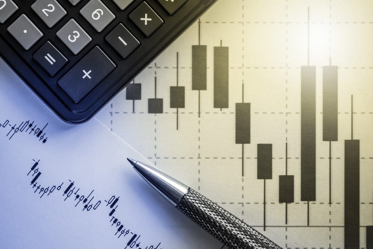 Calculator and pen beside stock chart