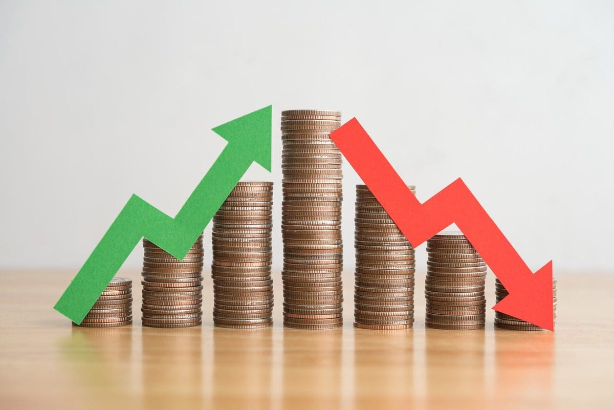 Financial chart represented by stacked coins with green and red arrows showing market volatility.