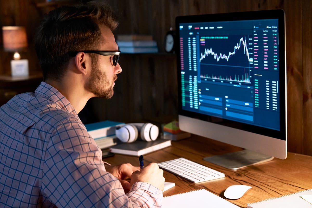 Professional investor reviewing financial data and market indexes on a high-resolution monitor.