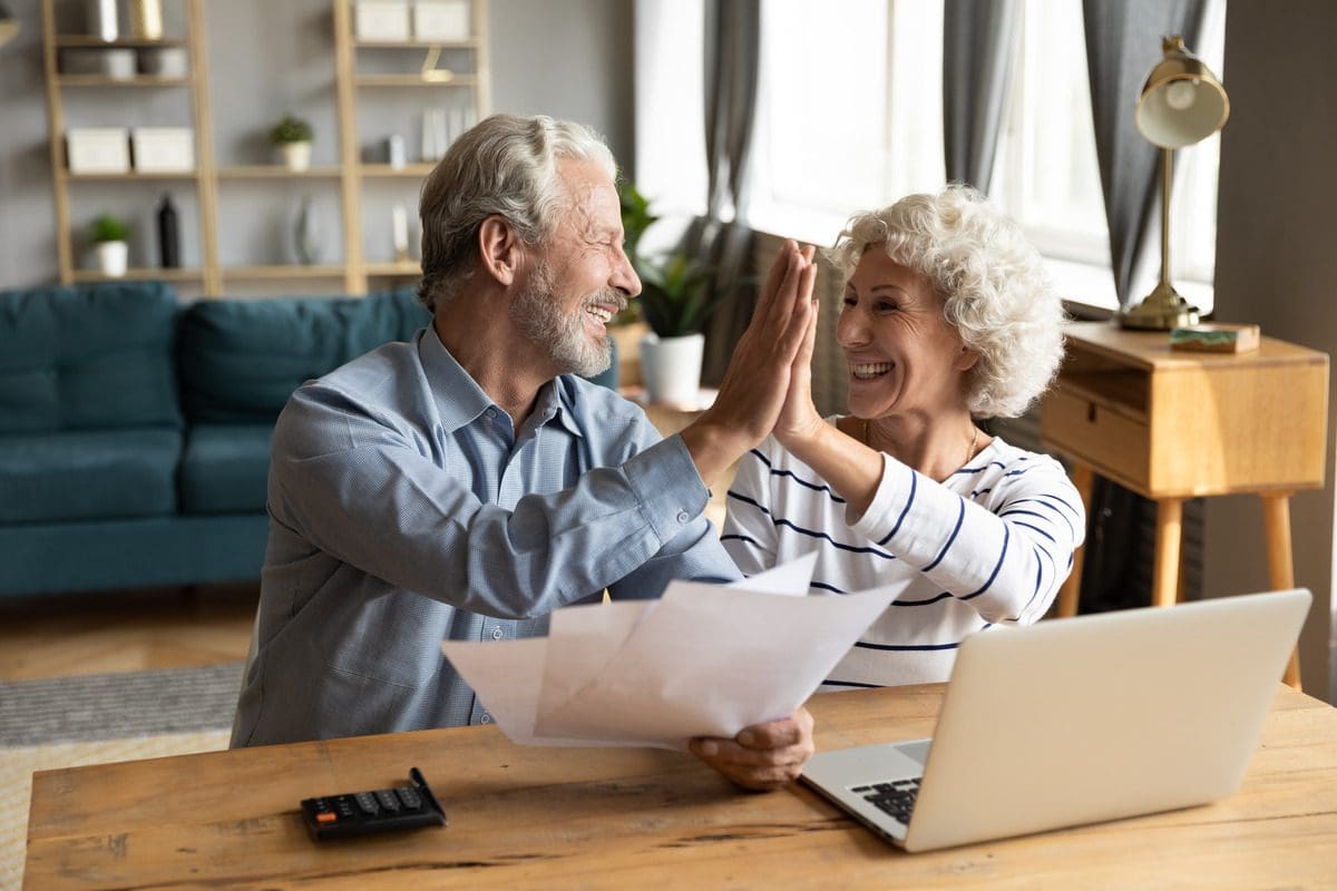 Mature couple celebrating a successful investment or retirement, symbolizing financial planning success.