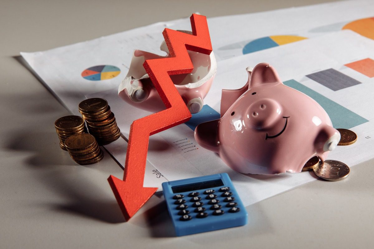 Conceptual image of financial loss featuring a broken piggy bank and a downward red arrow.