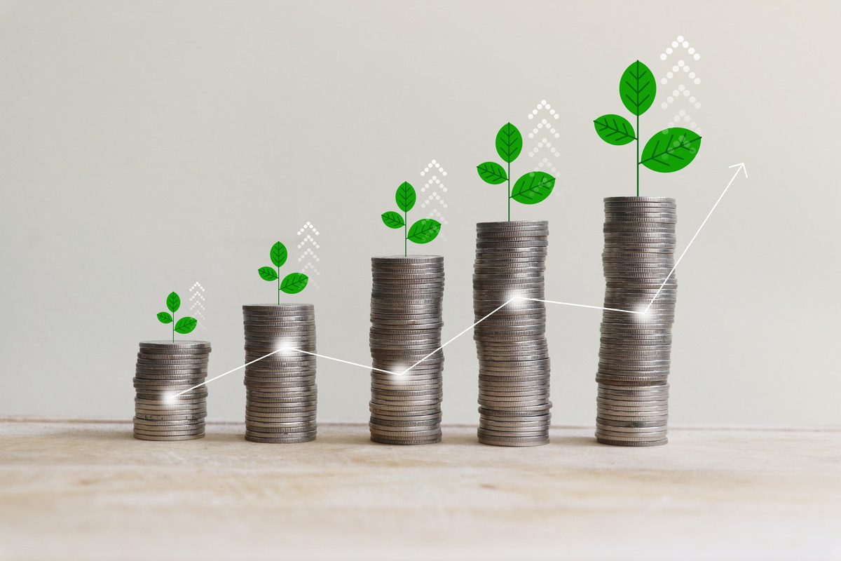 Green plant sprouts growing from stacked coins with a rising growth chart