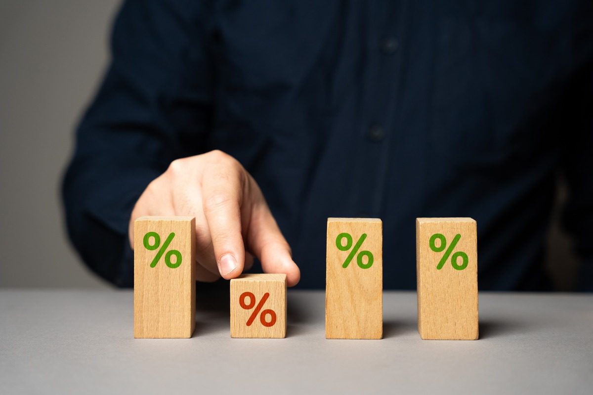 Close-up of wooden blocks with percentage symbols representing the calculation of student loan interest rates versus investment returns.