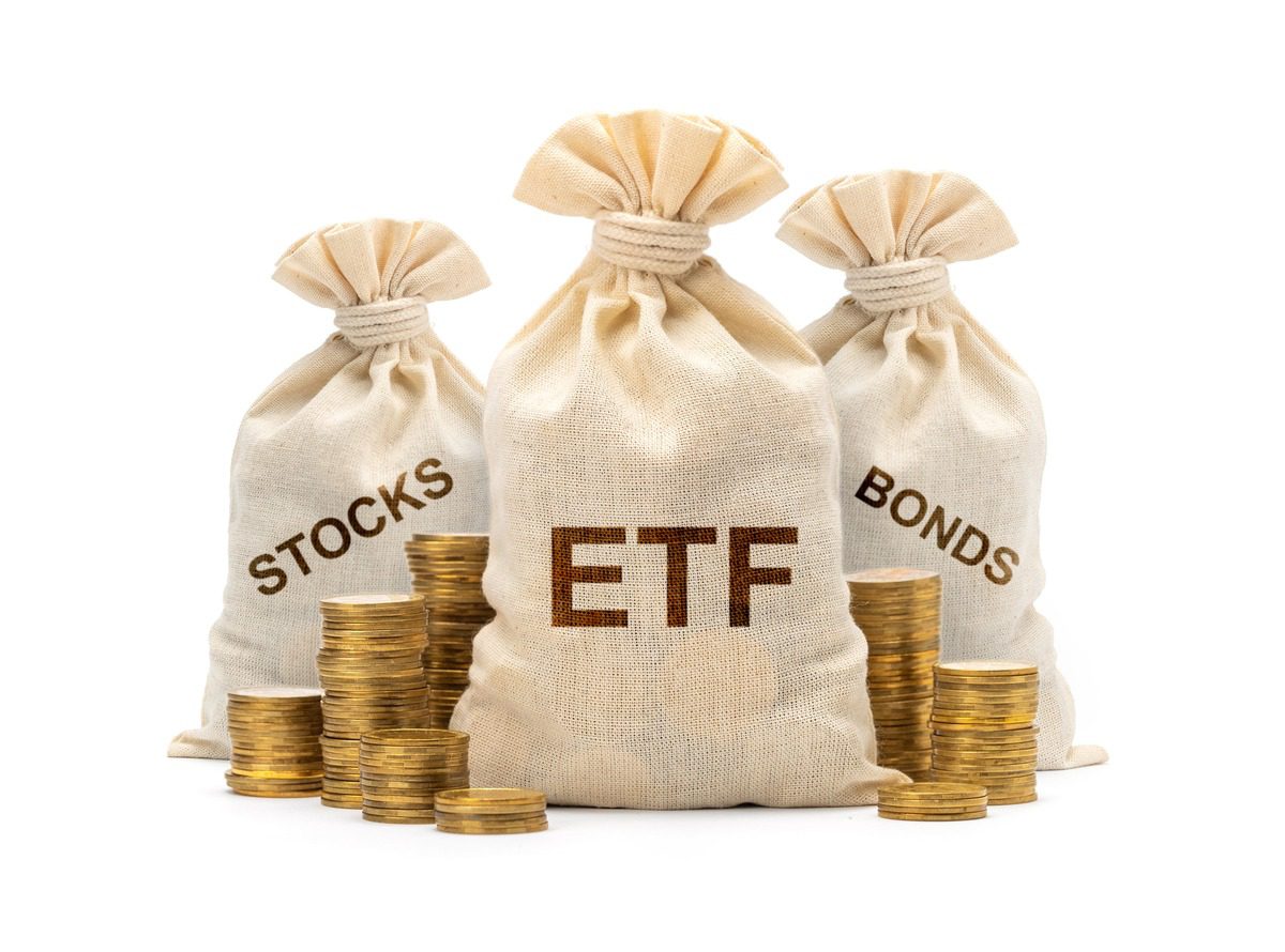 Burlap bags labeled Stocks, ETF, and Bonds next to gold coins illustrating investment diversification across different asset classes.