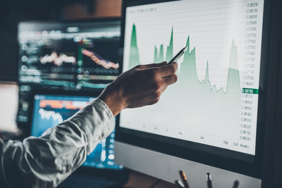 Person analyzing stock charts on screens