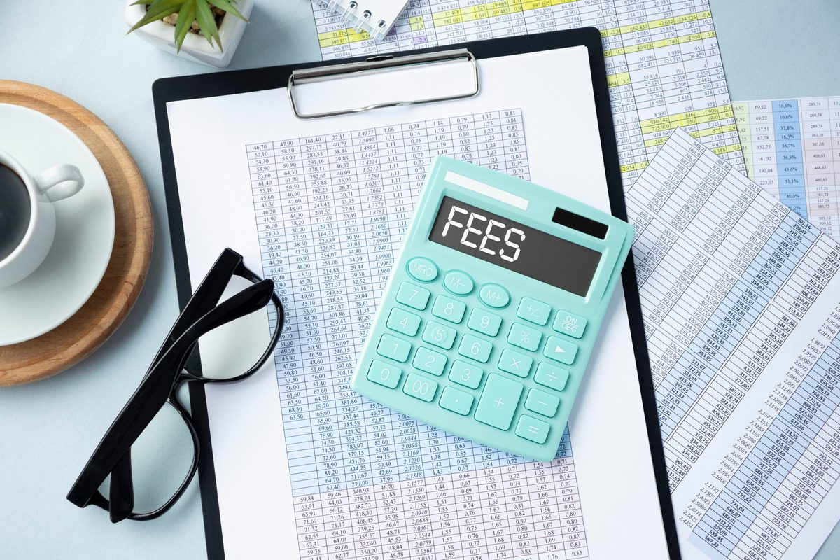 Clipboard with financial tables, calculator showing FEES, and glasses, representing financial planning and cost calculation.
