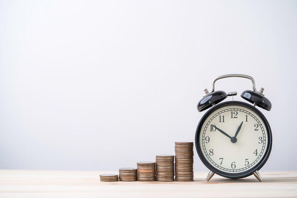 Alarm clock beside stacks of coins