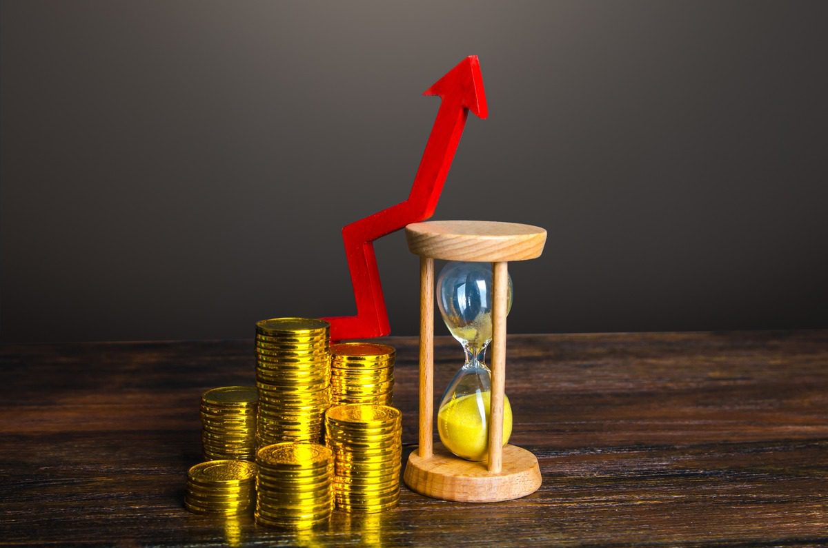 Conceptual image showing an increase in investing with stacked gold coins and an upward arrow.