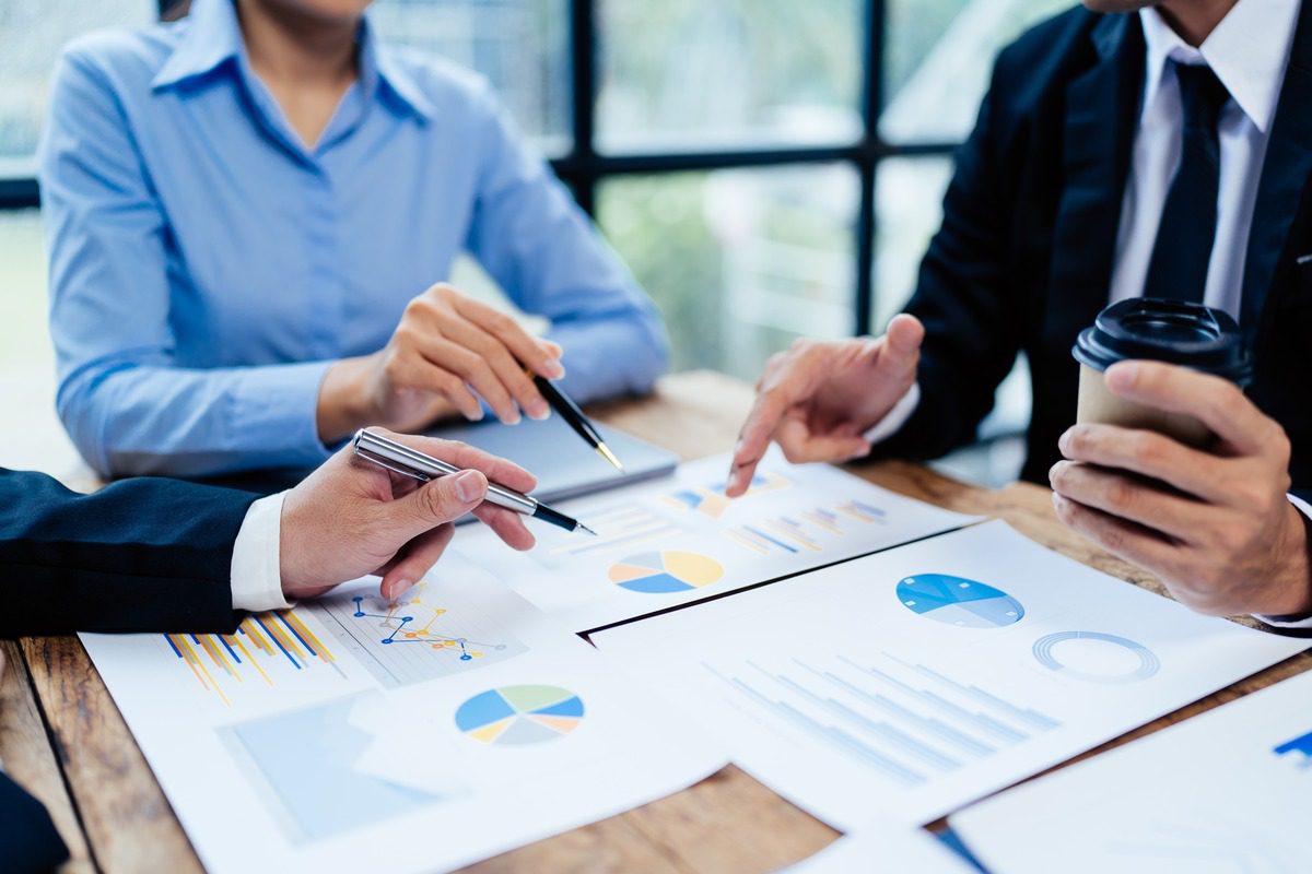 Financial professionals collaborating on data analysis and wealth management strategies using charts and graphs.