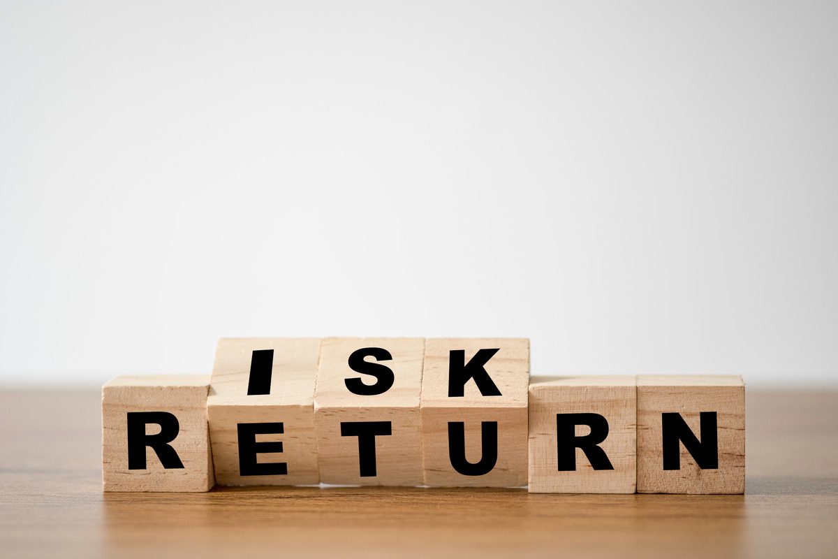 Wooden blocks on a table spelling out RISK and RETURN to illustrate financial balance.