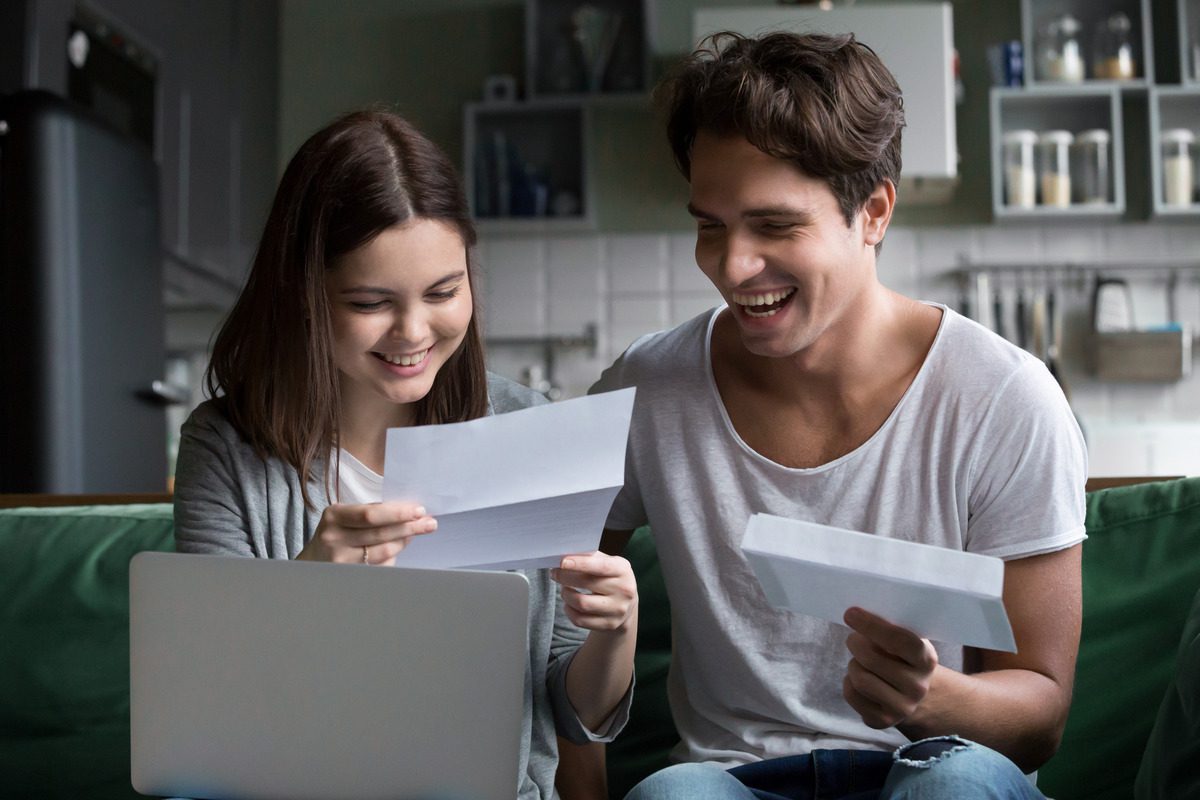 A young couple reviewing financial documents at home, illustrating the next generation of wealth management.