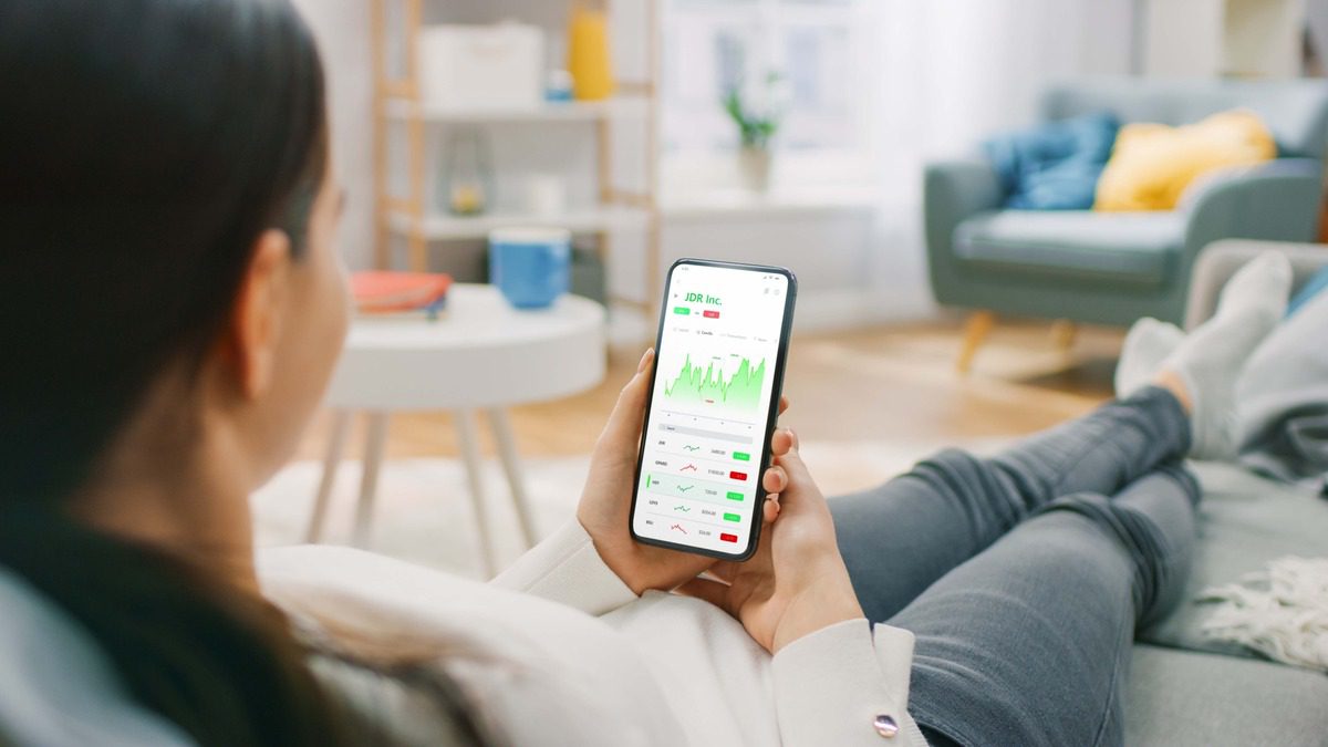 Woman using a mobile banking app to monitor investment portfolios and financial stability metrics.